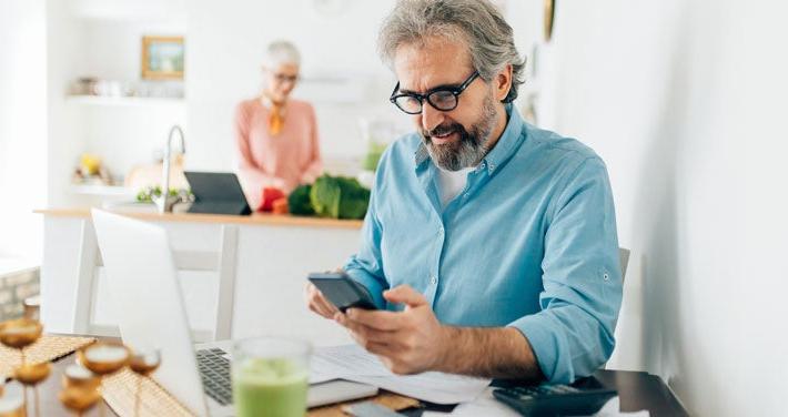 senior man using calculator at kitchen table